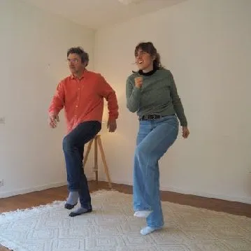 Deux personnes en mouvement, en équilibre sur une jambe, dans une salle de pratique