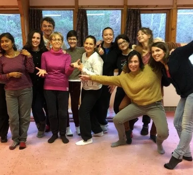 Une douzaine de stagiaires posent ensemble, bras ouverts et souriants, dans une salle de stage.