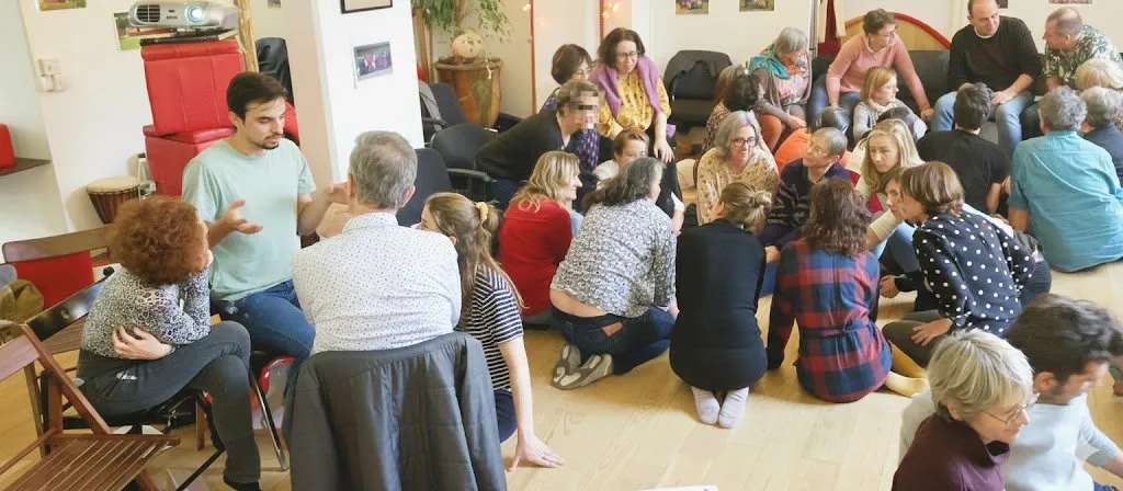 Un cercle de participants assis par terre et sur des chaises, en discussion avec un formateur