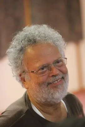 Portrait d’un homme âgé souriant, aux cheveux blancs bouclés.